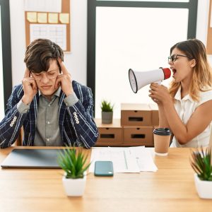 Businesswoman angry shouting her partner using megaphone at the office.