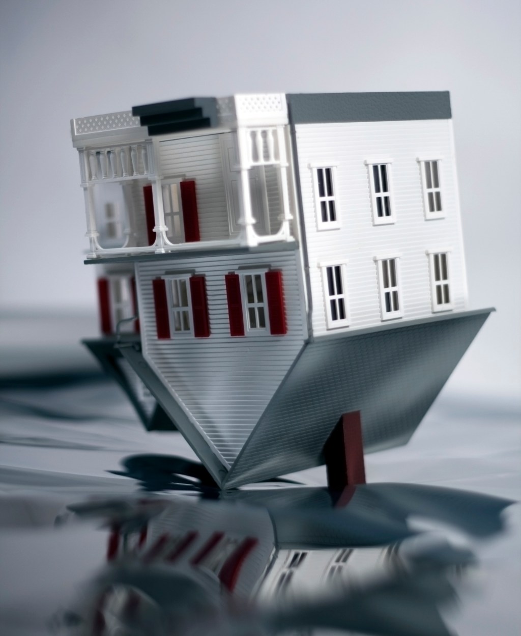 House turned upside down on reflective background.