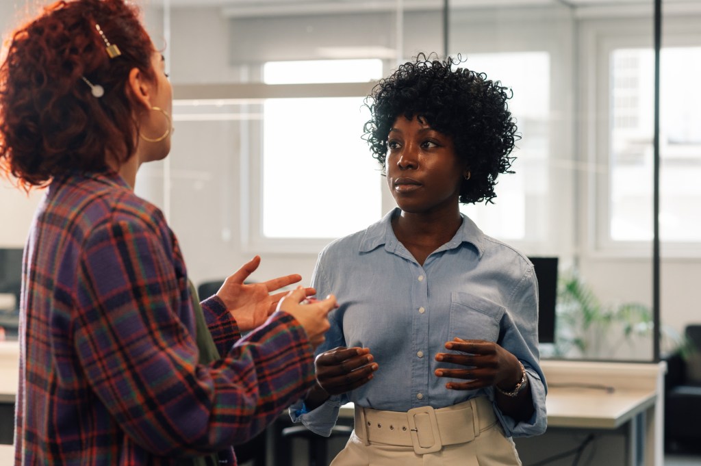 unnamed – 2026-10-01T085411.120 Portrait of a multicultural businesswoman standing with her colleague and listening while discussing assignment. An african american female executive is talking with project manager at office.