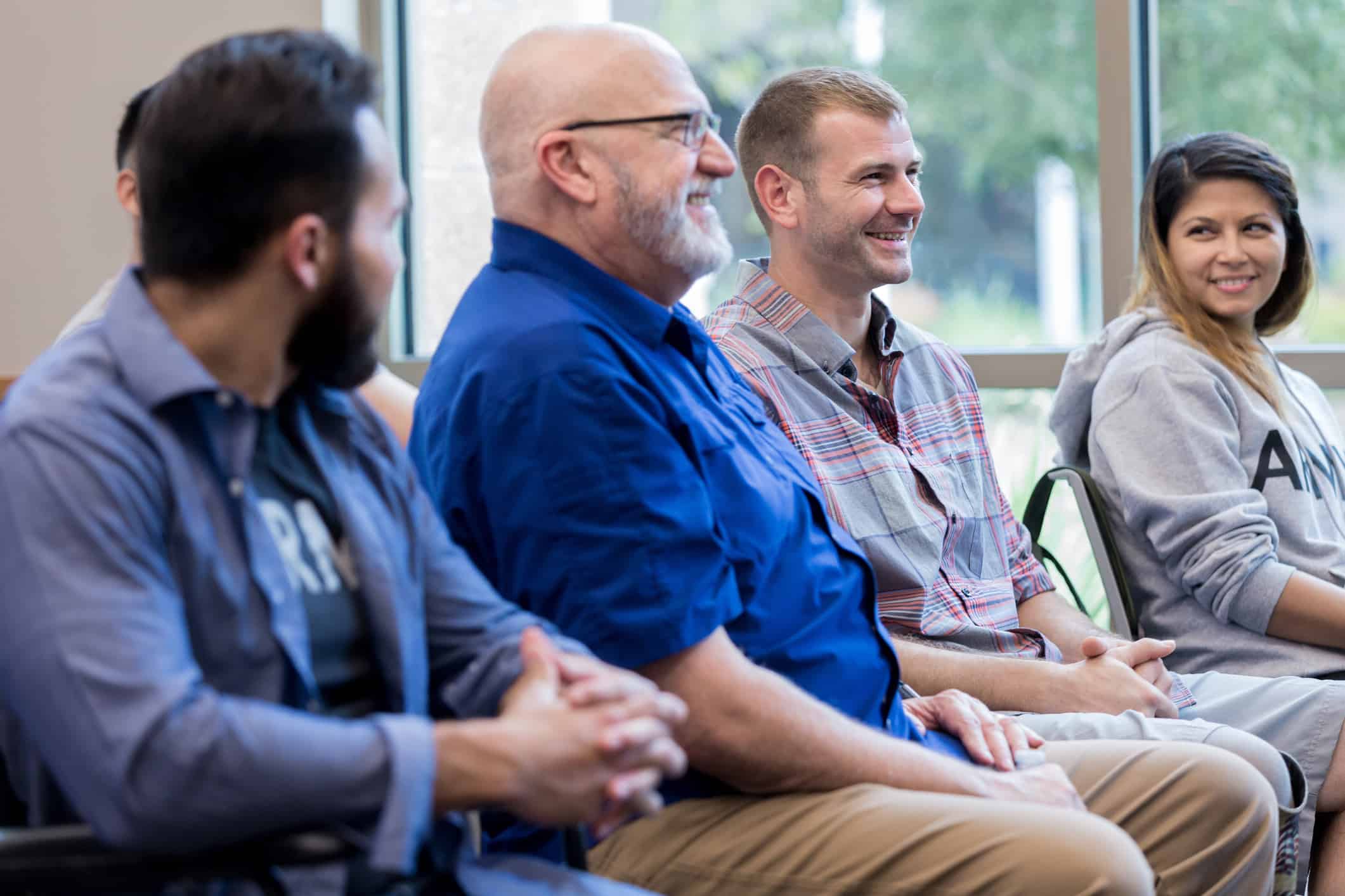 Smiling group of male and female military veterans enjoy attending a seminar for veterans.